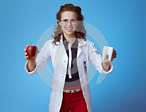 Medical practitioner woman showing red apple and white tooth