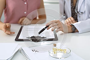 Medical prescription form, capsules and pills are lying against the background of a doctor and patient discussing health