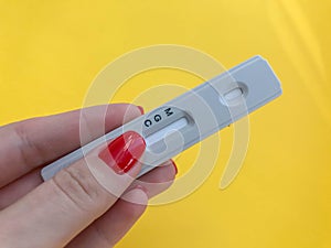 Medical procedures. coronavirus test on a bright yellow background. girl with bright red manicure holds a strip. IgG and IgM