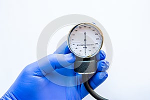 Medical professional, nurse or doctor holds in hand, wearing blue medical glove, sphygmomanometer showing level of diastolic and s photo