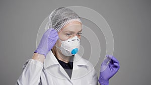 Medical professional woman is putting filtering half mask with exhalation valve on her face, protection