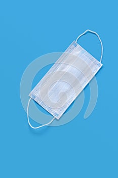 Medical protective mask on a blue background. The disposable surgical face mask covers the mouth and nose. Health care and medical