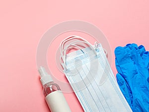 Medical protective mask, latex gloves, hand sanitizer on a pastel pink background. Individual, disposable hygiene equipment.