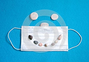 medical protective mask, stones. Summer concept, tourism, pandemic, flat lay, copy space, top view.