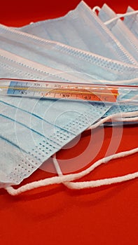 Medical protective masks and mercury thermometer on a red background