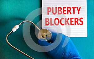 Medical and puberty blockers symbol. Words `puberty blockers` on white note. Doctor hand in blue glove and stethoscope. Beautifu