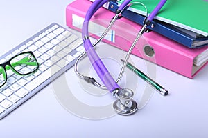 Medical record concept with stethoscope over pile of folders. Keyboard, glasses, pen, RX prescription. Selective focus