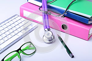 Medical record concept with stethoscope over pile of folders. Keyboard, glasses, pen, RX prescription. Selective focus