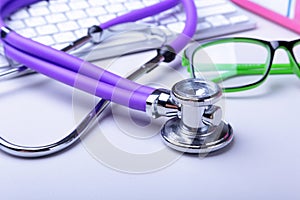 Medical record concept with stethoscope over pile of folders. Keyboard, glasses, pen, RX prescription. Selective focus