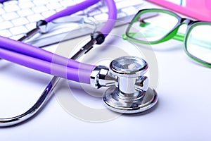 Medical record concept with stethoscope over pile of folders. Keyboard, glasses, pen, RX prescription. Selective focus