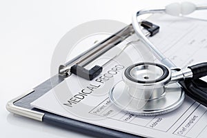 Medical record and stethoscope on white background.