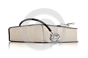 Medical reference book with a stethoscope on white