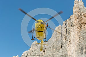 Medical rescue helicopter flying rescue injured climber on the Tre Cime. Italy, Dolomites