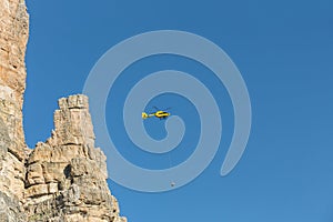 Medical rescue helicopter flying rescue injured climber on the Tre Cime. Italy, Dolomites