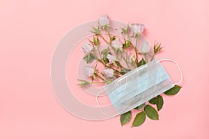 Medical respiratory protective face mask and delicate roses on a pink background, the theme of coronavirus and covid-19