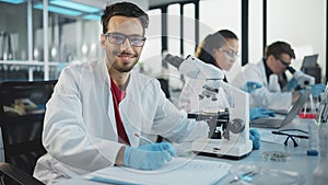 Medical Science Laboratory: Handsome Latin Scientist Analysing Samples and Uses Microscope, Looking