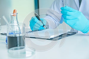 Medical science or male Compiling an Analysis Report in laboratory room research performs tests with blue liquid on test tube, photo