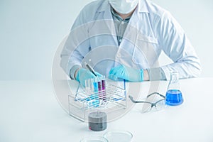 Medical science or male Compiling an Analysis Report in laboratory room research performs tests with blue liquid on test tube,