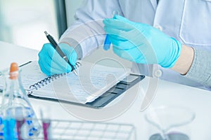 Medical science or male Compiling an Analysis Report in laboratory room research performs tests with blue liquid on test tube, photo