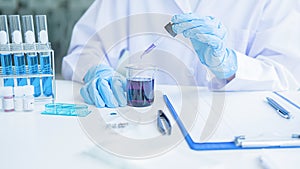 Medical or scientific researcher or man doctor looking at a test tube of clear solution in a laboratory