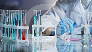 Medical scientist conducting test, observing reactions in glass flasks, research