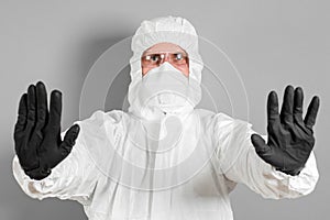 A medical scientist or a policeman wears protective clothing and shows a stop sign. The concept of health and crime