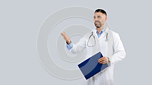 Medical services concept. Male doctor physician in uniform with clipboard in hand looking aside and talking, copy space