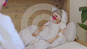 Medical sister with a red nose plays with a girl in her hospital ward