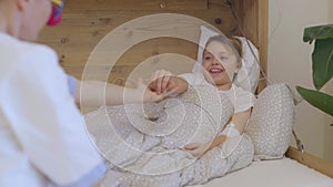 Medical sister with a red nose plays with a girl in her hospital ward