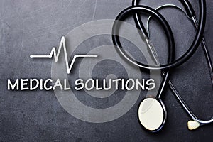 Medical solutions text on blackboard with stethoscope and heartbeat rate