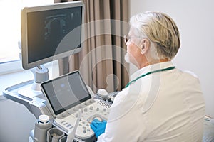 Medical specialist making ultrasonic diagnostics in hospital