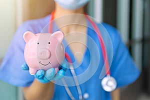 Medical staff hand showing piggy bank smile for saving money for future healthcare health insurance concept