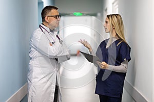 Medical Staff Having Discussion In Modern Hospital Corridor