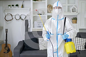 A medical staff in PPE suit is using disinfectant spray in living room, Covid-19 protection , disinfection concept