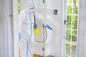 Medical staff in PPE suit is using disinfectant spray in living room, Covid-19 protection , disinfection concept