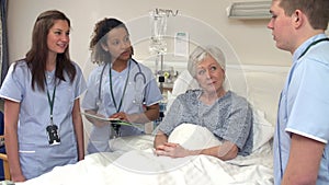 Medical Staff On Rounds Standing By Male Patient's Bed