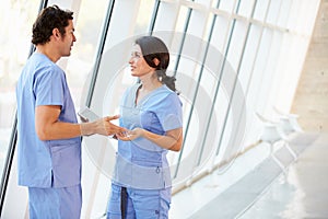 Medical Staff Talking In Hospital Corridor With Digital Tablet