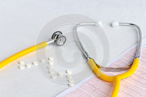 Medical stethoscope on cardiogram chart with a pills, tablets and capsules, close up