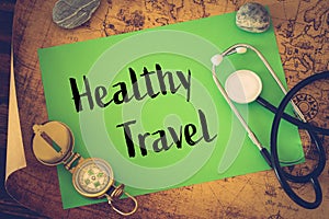 Medical stethoscope, compass and a card with the words `Healthy Travel` on the background of an old map of the world, The concept