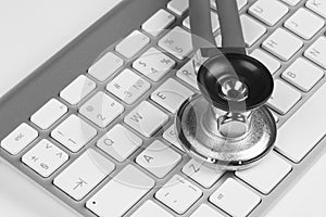 Medical stethoscope on computer keyboard. Concept of computer support. Black and white.