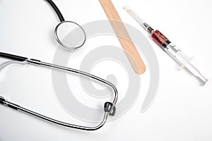 Medical stethoscope, disposable spatula, disposable mask and syringe with blood samples on a white isolated background