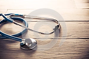 Medical stethoscope dramatically lit on a wooden table