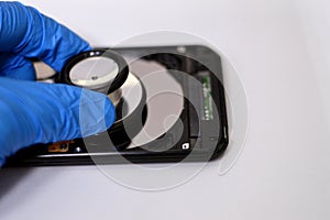 A medical stethoscope on HDD platters and spindle motor, hard disk drive disassembled damaged components, computer maintenance,