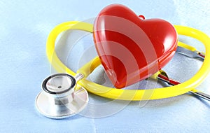 Medical stethoscope head and red toy heart lying on cardiogram chart closeup. help, prophylaxis, disease prevention or insurance