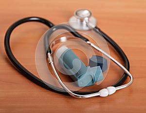 Medical stethoscope and inhaler on the background of table.