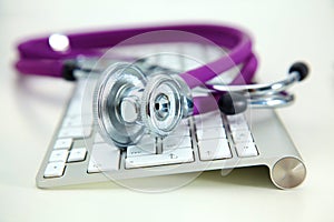 Medical stethoscope lies on a computer keyboard