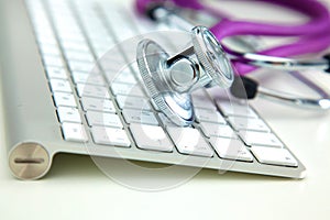 Medical stethoscope lies on a computer keyboard