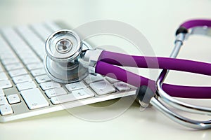 Medical stethoscope lies on a computer keyboard