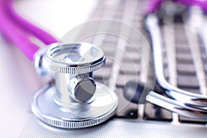 Medical stethoscope lying on a computer keyboard, cup of coffee