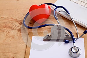 Medical stethoscope lying on a computer keyboard, documents